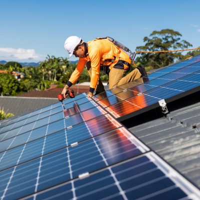 Solar panel technician with drill installing solar panels Solar panel technician with drill installing solar panels on house roof on a sunny day.